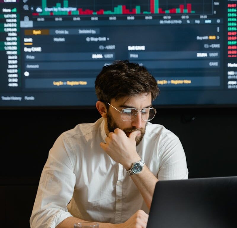 Bearded Man in White Dress Shirt Wearing Eyeglasses Sitting in Front of Laptop Feeling Pensive